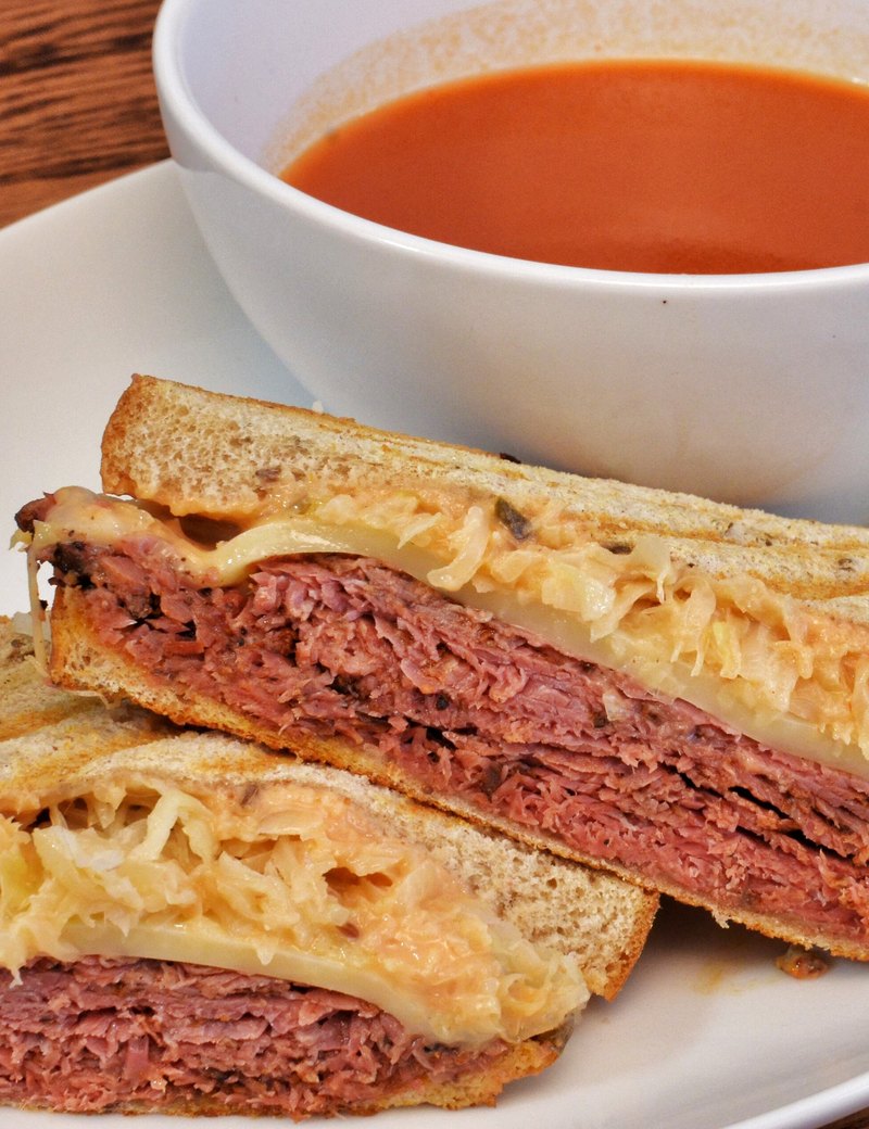 Un panini grillé coupé en deux, servi avec un bol de soupe