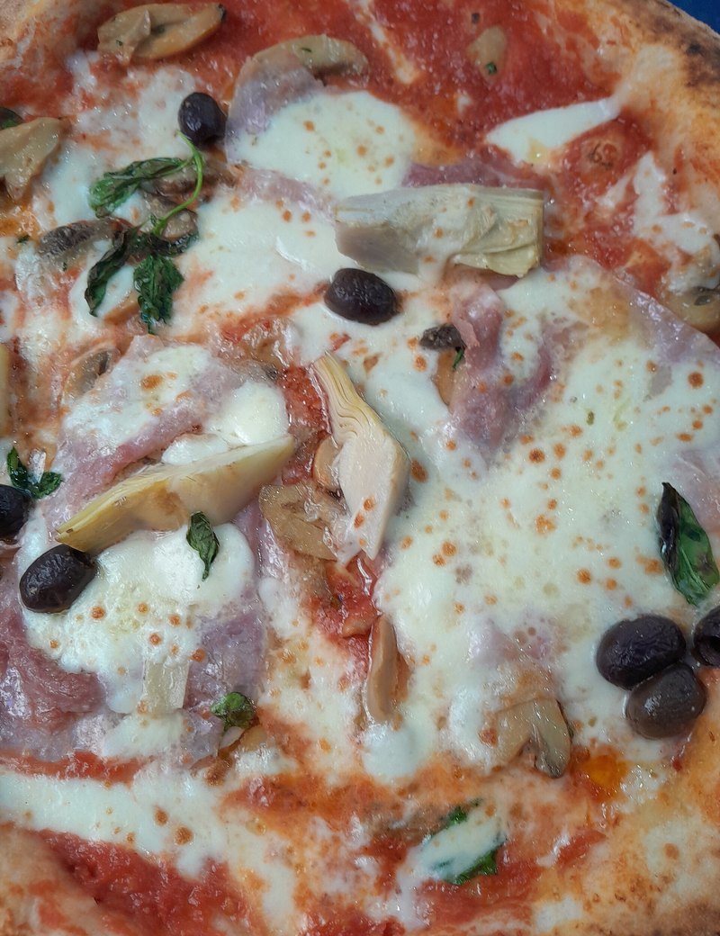 Pizza garnie de champignons, artichauts, olives et jambon