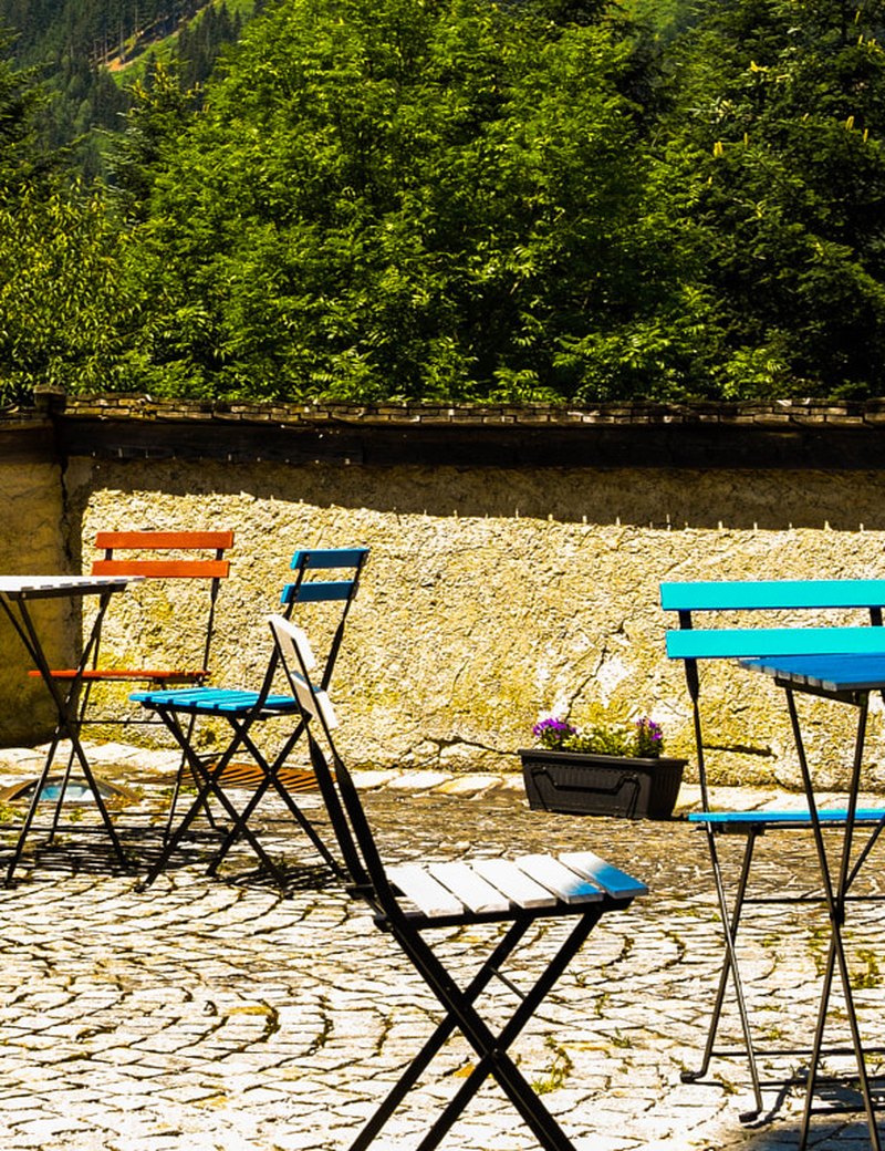 Tables et chaises de bistrot colorées sur une terrasse en pierre